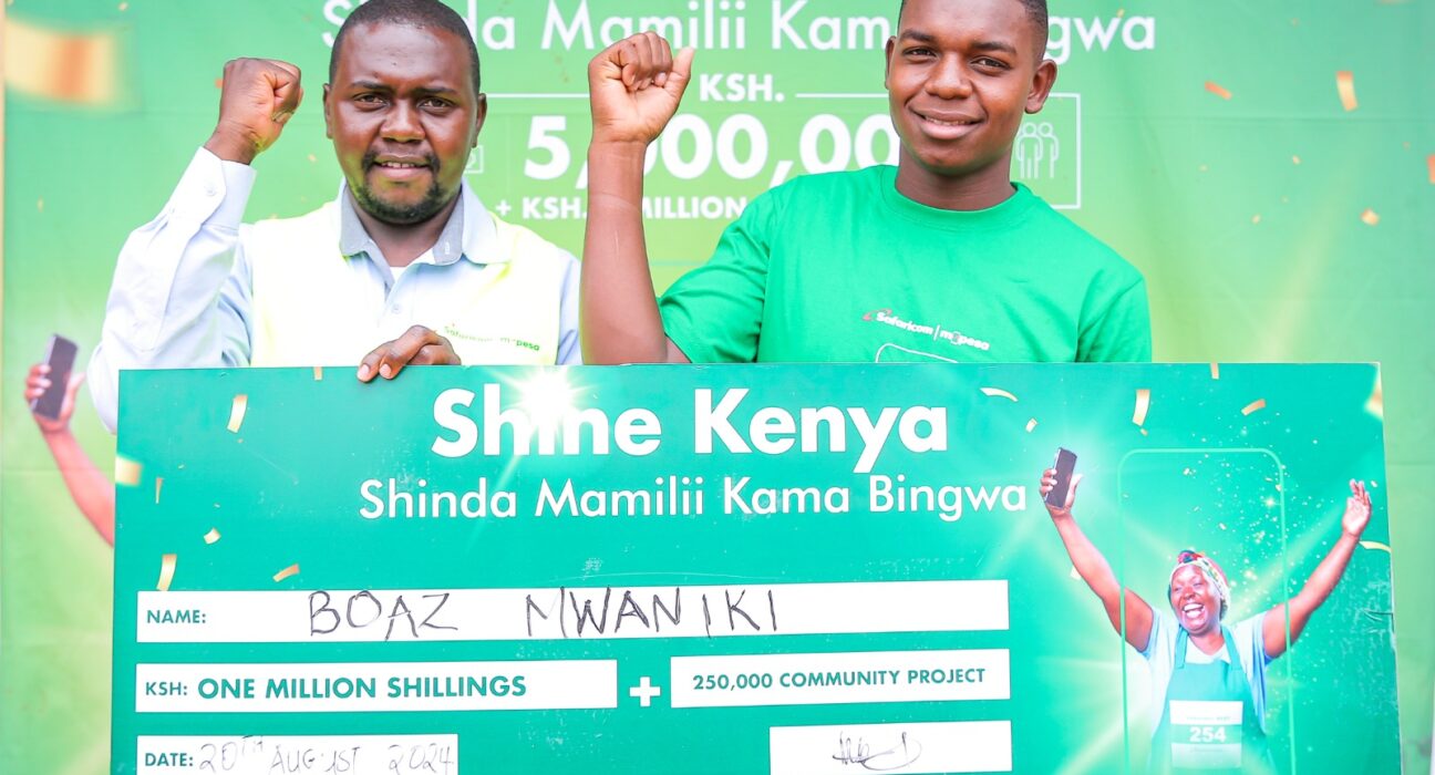 Cosmus Maluki -Trade Development Representative Mwingi North at Safaricom (Left) handing over a dummy check to Boaz Mwaniki, winner of Ksh.1 million during the Shine Kenya Shinda Mamilii Kama Bingwa award ceremony held at Migwani in Kitui County.