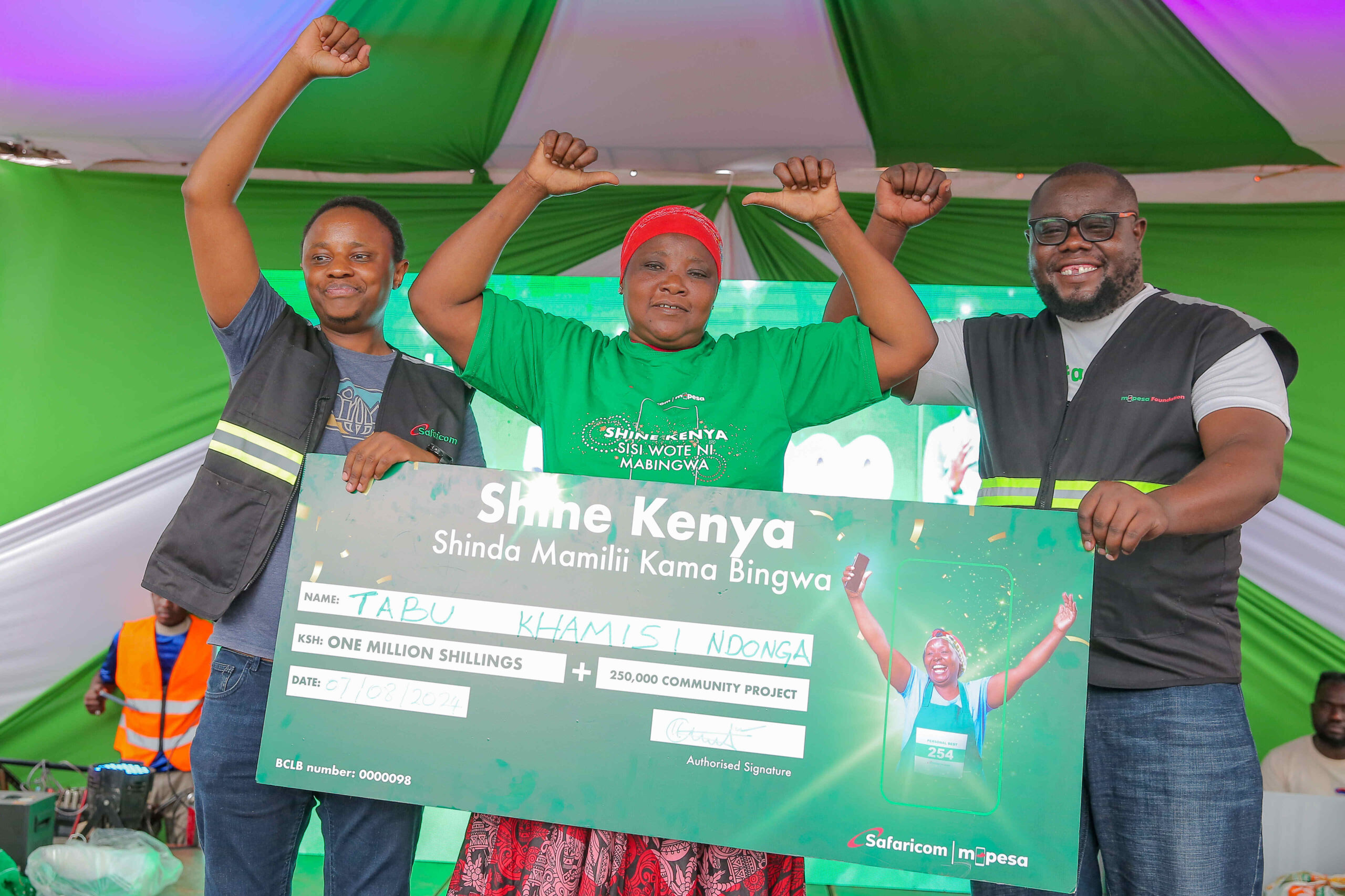 Martin Mugera, Marketing Manager at Safaricom(Left) and Cosmas Albert, Territory Business Lead at Safaricom, Kilifi (Right) handing over Sh. 1 Milion dummy cheque to Tabu Khamisi Ndonga at the awards ceremony of Shine Kenya Shinda Mamili kama Bingwa Campaign held at Mtwapa in Kilifi County