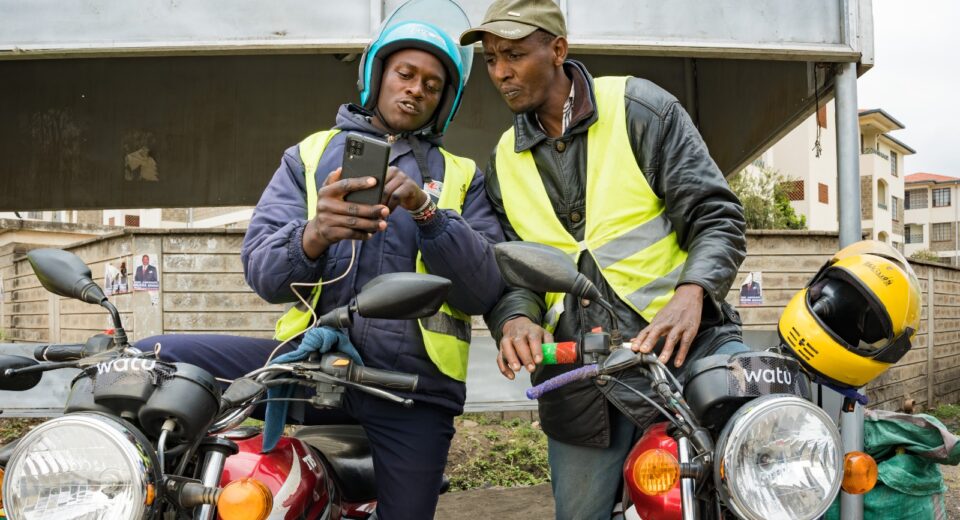 Boda Boda riders reviewing some operating features on a smartphone