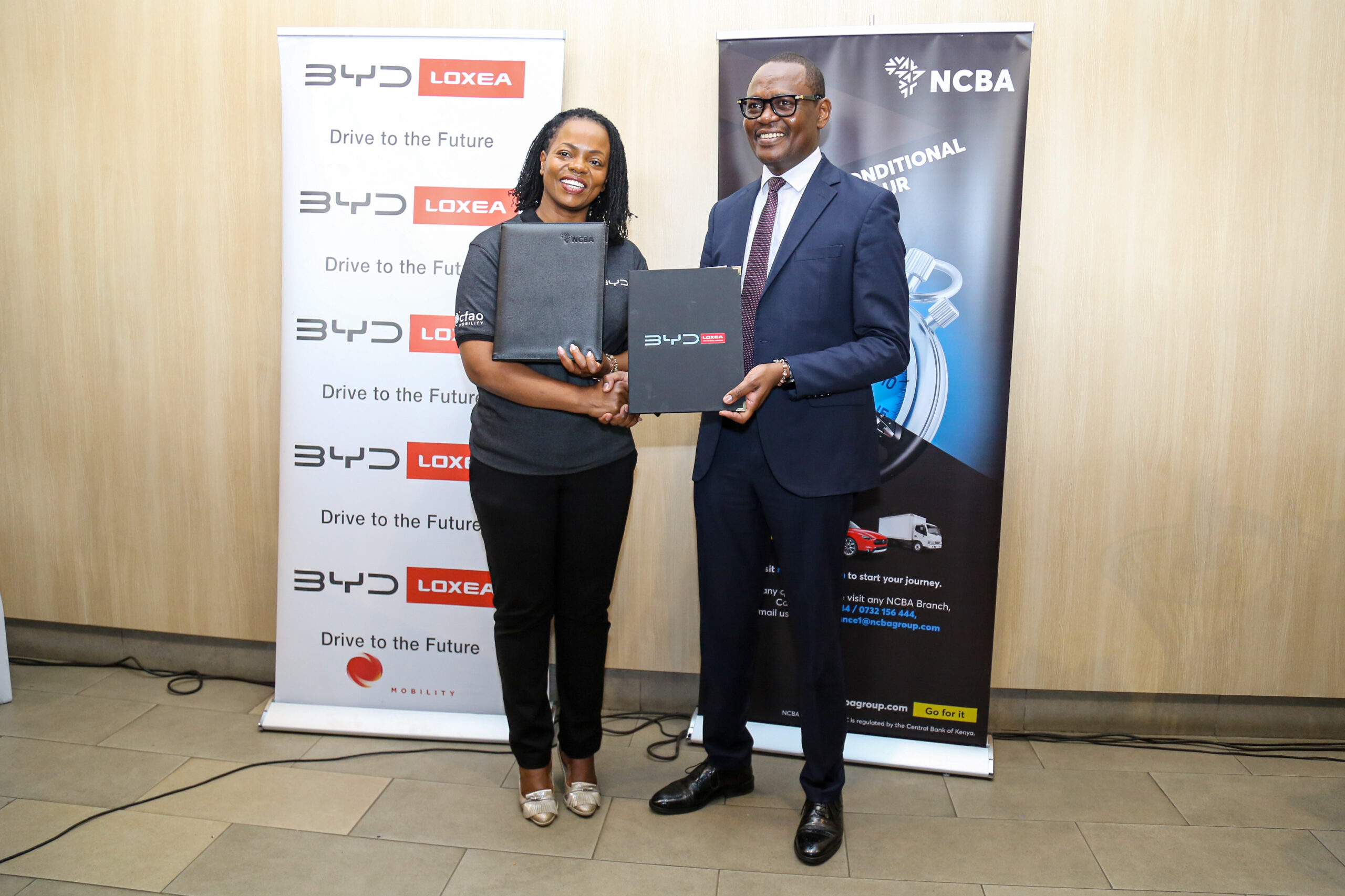 Loxea Managing Director, Jennifer Kinyoe (left) and, NCBA Group Director of Asset Finance & Business Solutions, Lennox Mugambi (right), and during the signing and exchange of documents to seal the strategic partnership between NCBA and BYD by Loxea.