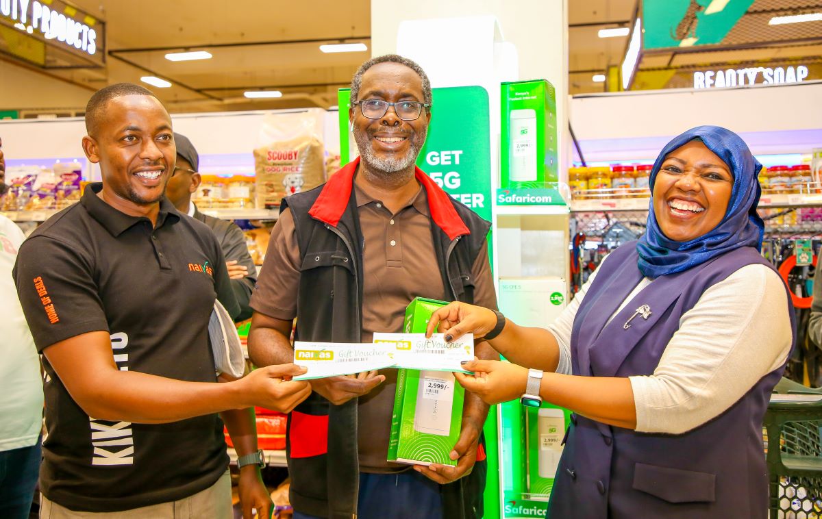 Fawzia Ali, Chief Consumer Business Officer at Safaricom PLC (Right) awards customer Afurika Juvenal with Naivas shopping vouchers after he purchased a Safaricom 5G router. Assisting in the presentation is Dennis Makori, Senior Commercial Manager at Naivas Supermarket. The award was presented during the 5G partnership launch between Safaricom and Naivas Supermarket held at the Imara Imara Mall in Nairobi.