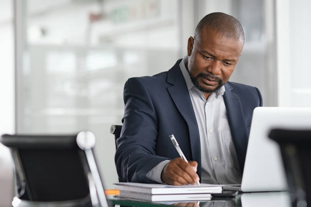 Businessman looking at Laptop Taking Notes