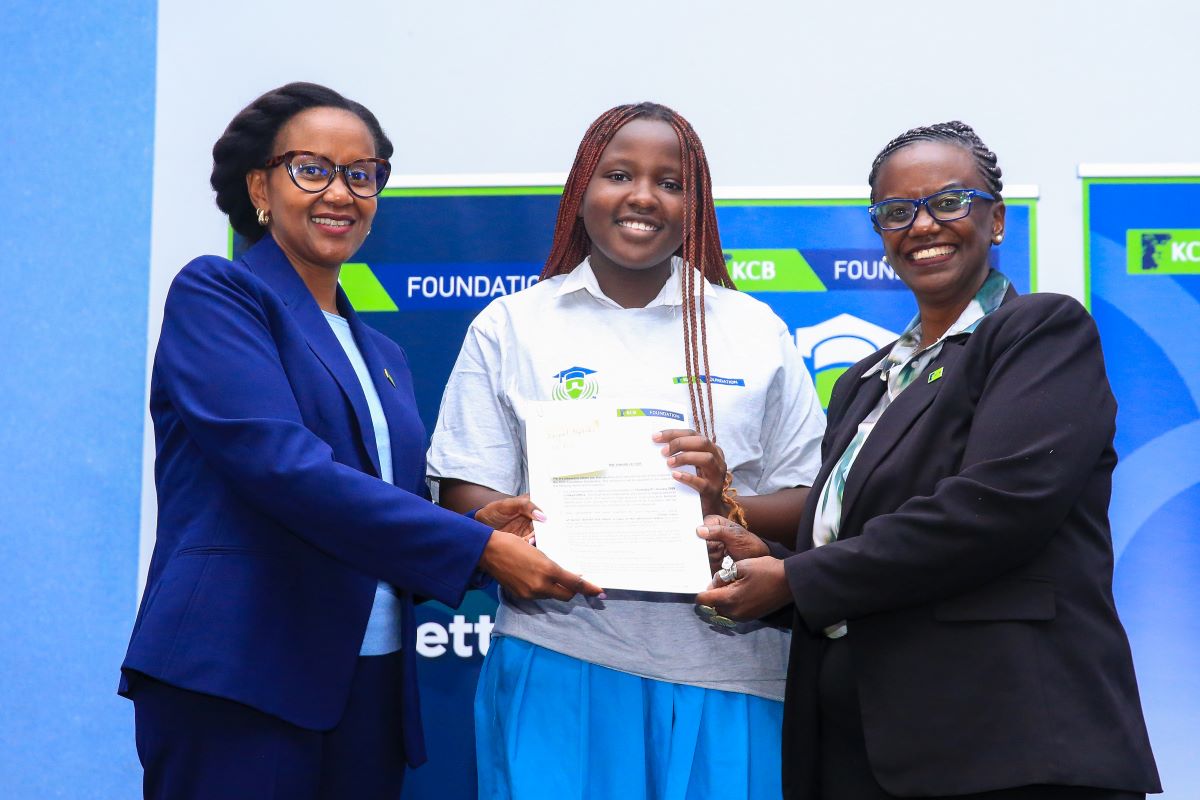 Rosalind Gichuru, Group Director of Marketing and Communications at KCB Group (left), and Mendi Njonjo, Director of the KCB Foundation (right), present award letter to Abigael Nyokabi, a beneficiary of the KCB Foundation Scholarship, during the flag-off ceremony at the KCB Leadership Centre.
